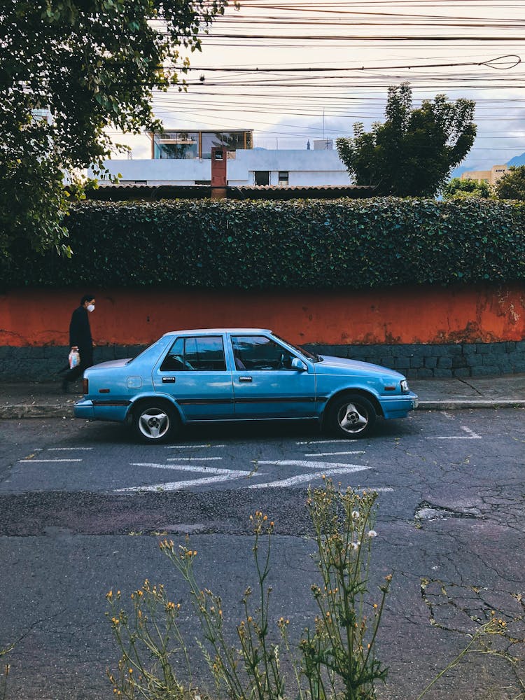 A Vintage Hyundai Excel Parked On The Side Of The Street