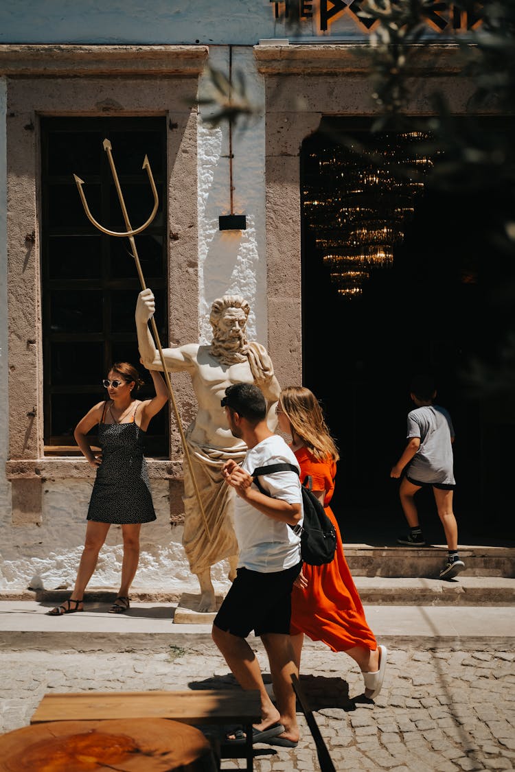 People Walking Near Poseidon Statue On Street