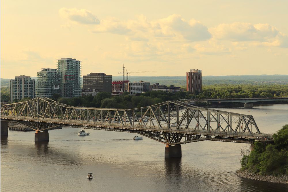 Aerial view of Alexandra Bridge spanning the Ottawa River, with Gatineau skyline in the background.