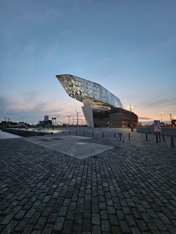Havenhuis Port House in Antwerp, Belgium at twilight, the iconic headquarters of the Port of Antwerp reflecting on the water