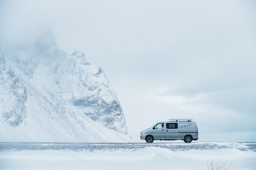 A van is parked in the snow near a mountain