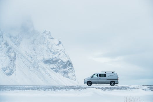 A van traverses the snowy roads of Iceland near towering icy mountains, capturing the spirit of winter adventure.