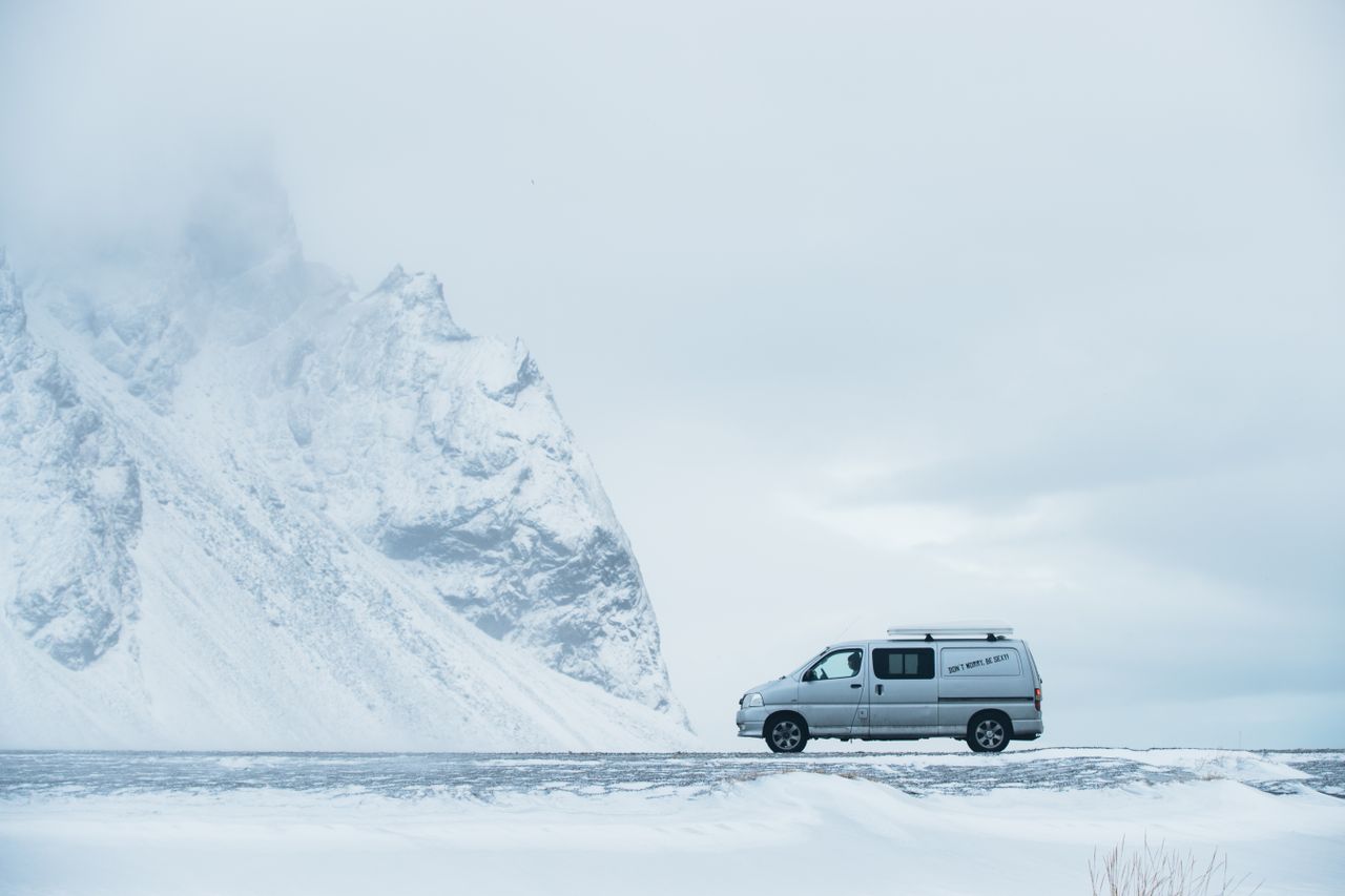 a van traverses the snowy roads of iceland near towering icy mountains