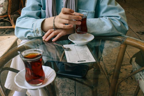 Hands of Person Sittin by Table with Turkish Tea