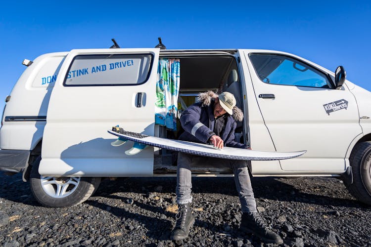 Man Sitting With Surfboard In Van