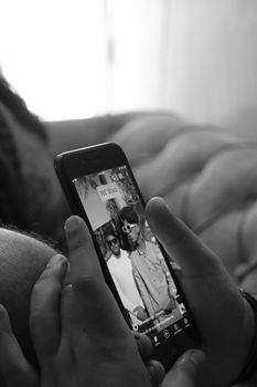 Black and white image of hands using a smartphone with an image displayed on screen in an indoor setting.