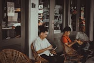 咖啡馆外，三名男子坐在椅子上玩手机