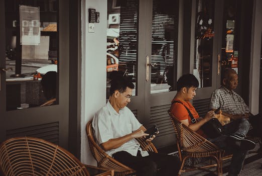 咖啡馆外，三名男子坐在椅子上玩手机