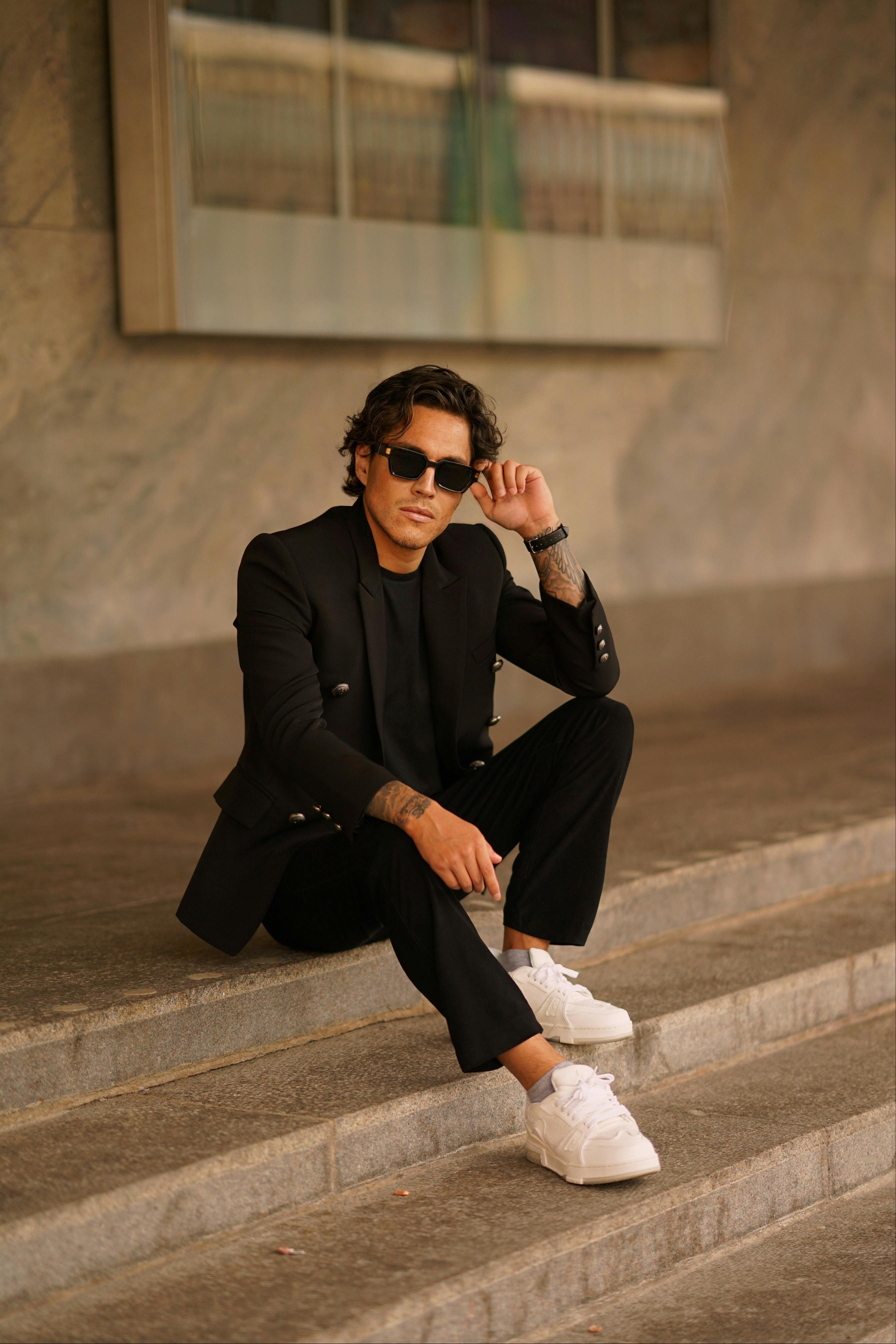 young, handsome guy in a white T-shirt, black, leather jacket and black  pants is on the street, n the T-shirt sunglasses. model, city walk, live  style.in white sneakers - Stock Image -