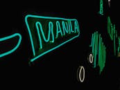 在黑色背景下，充满活力的霓虹灯标志以绿色显示“马尼拉”，营造出现代而艺术的感觉