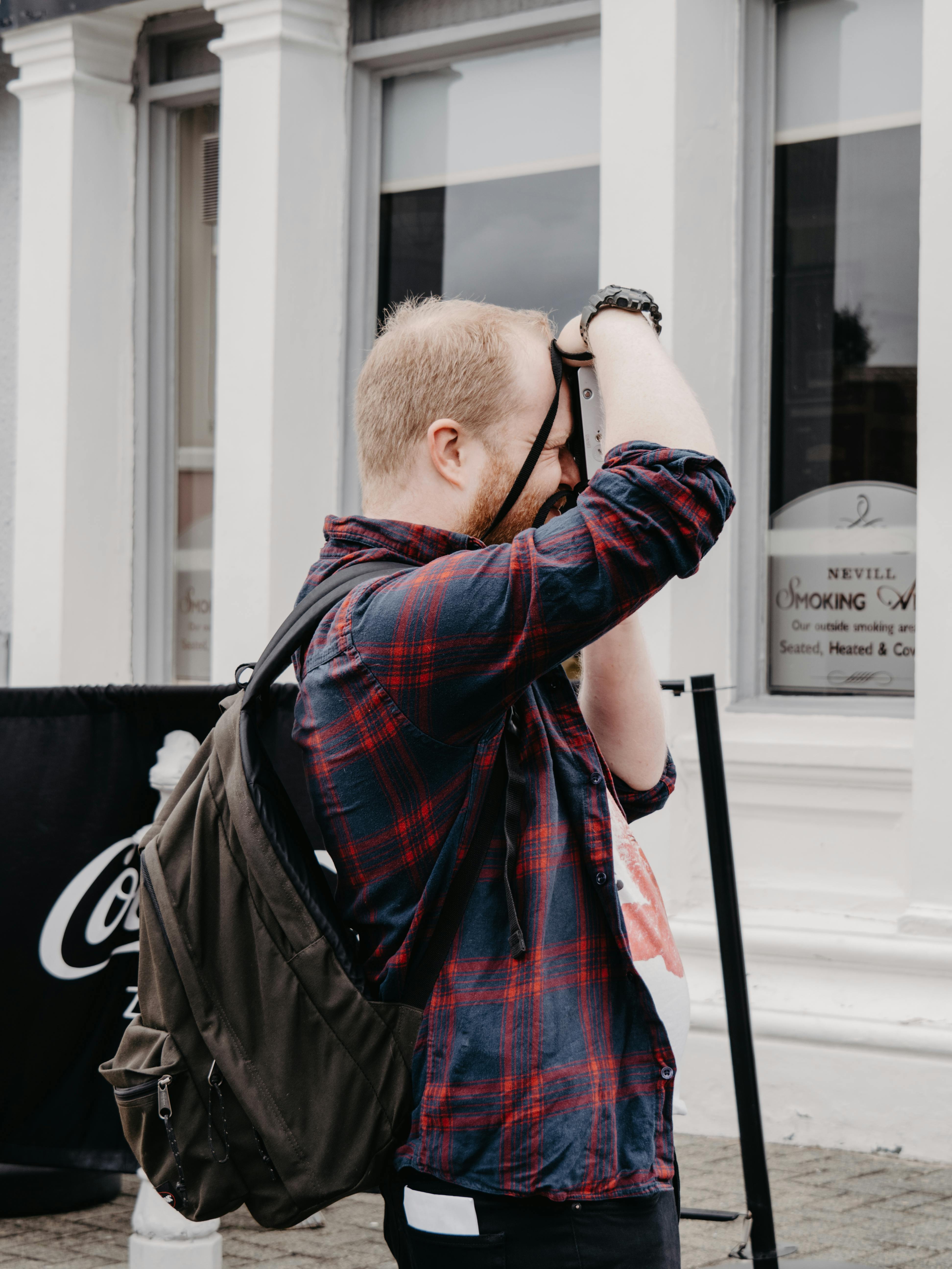 Casual tourist with a backpack takes urban photos in city streets.