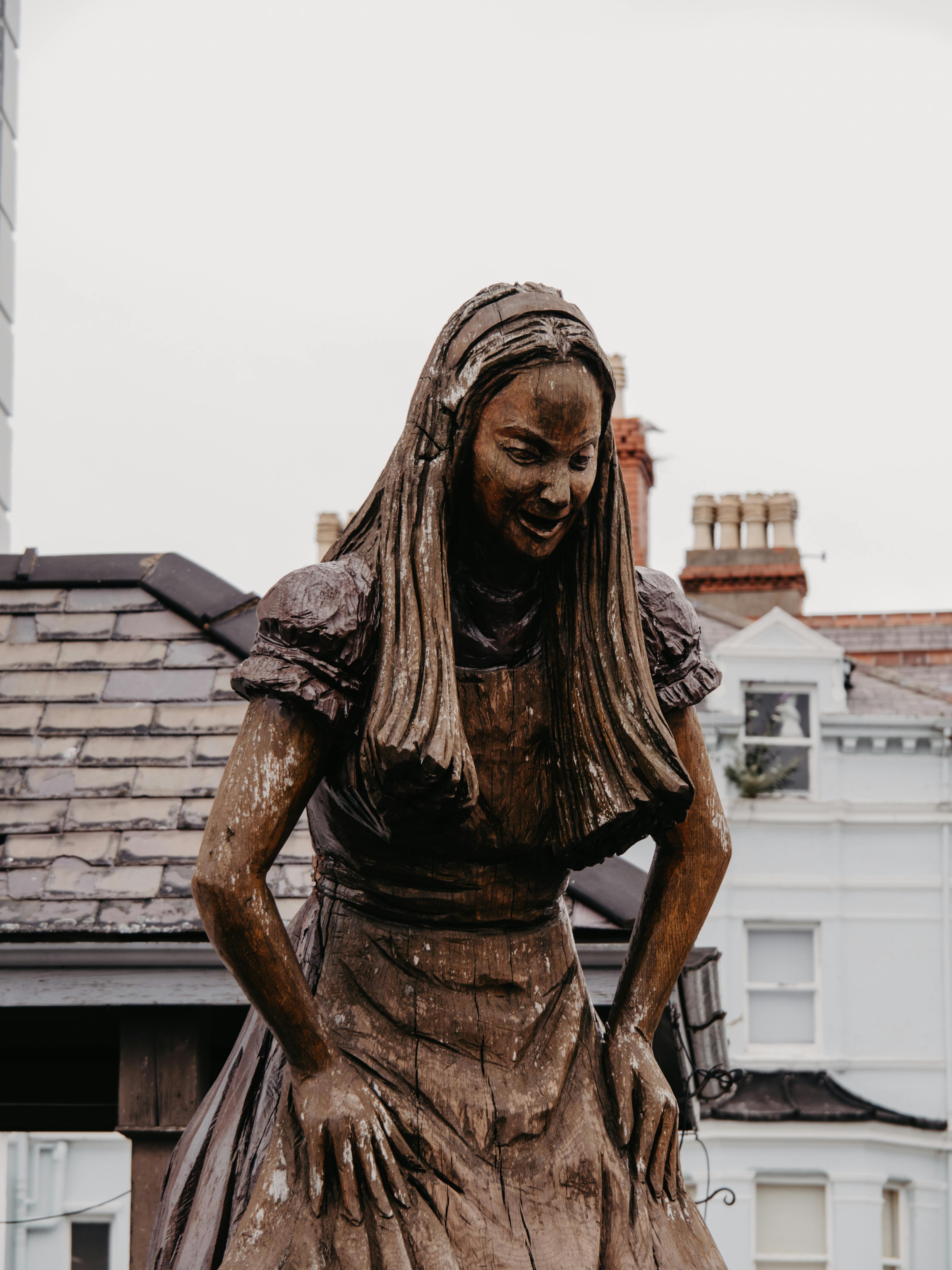 Wooden statue of Alice from Alice in Wonderland located in Llandudno, Wales.