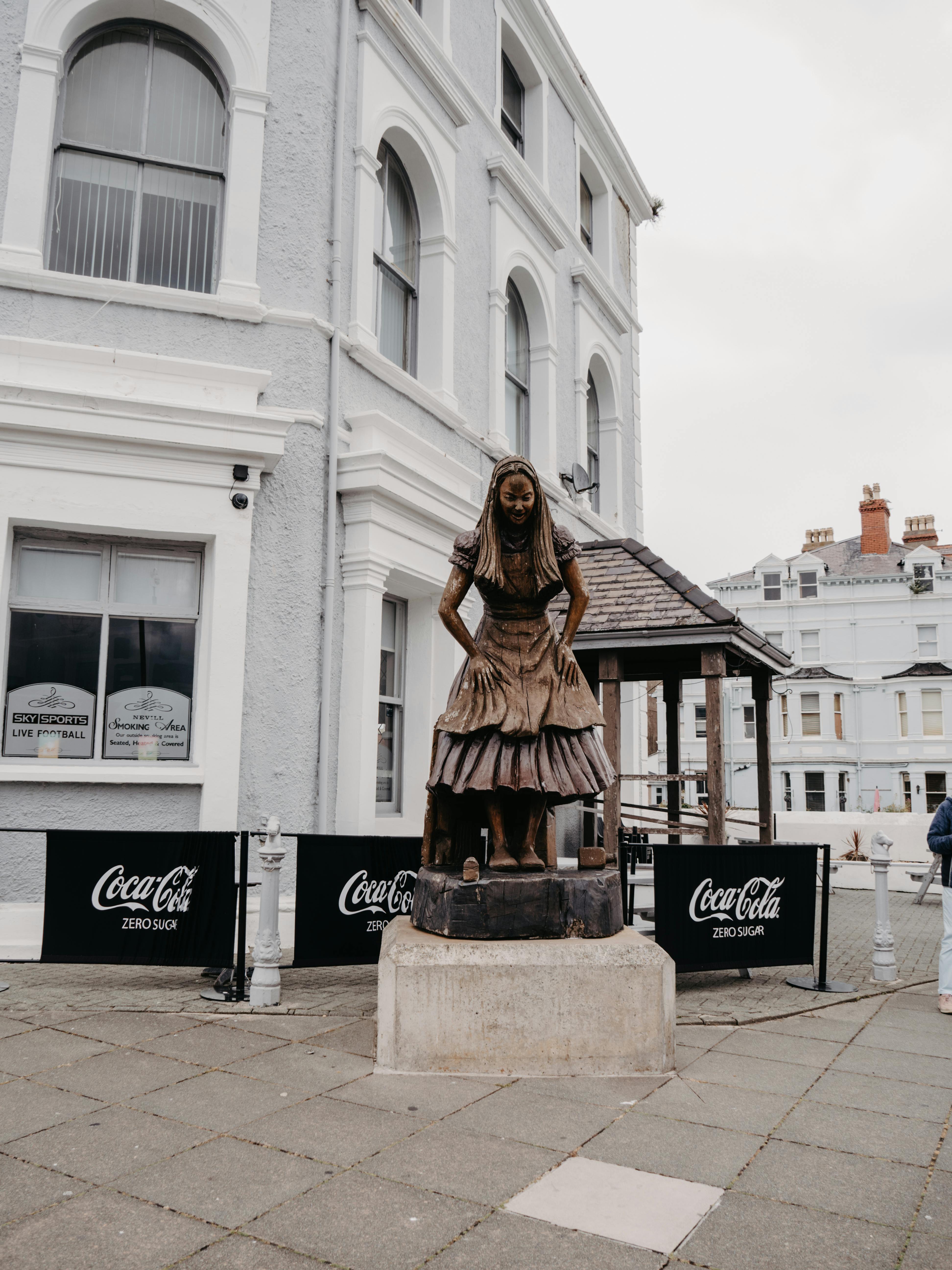 Explore the Alice in Wonderland statue in Llandudno, Wales, set in a charming urban landscape.