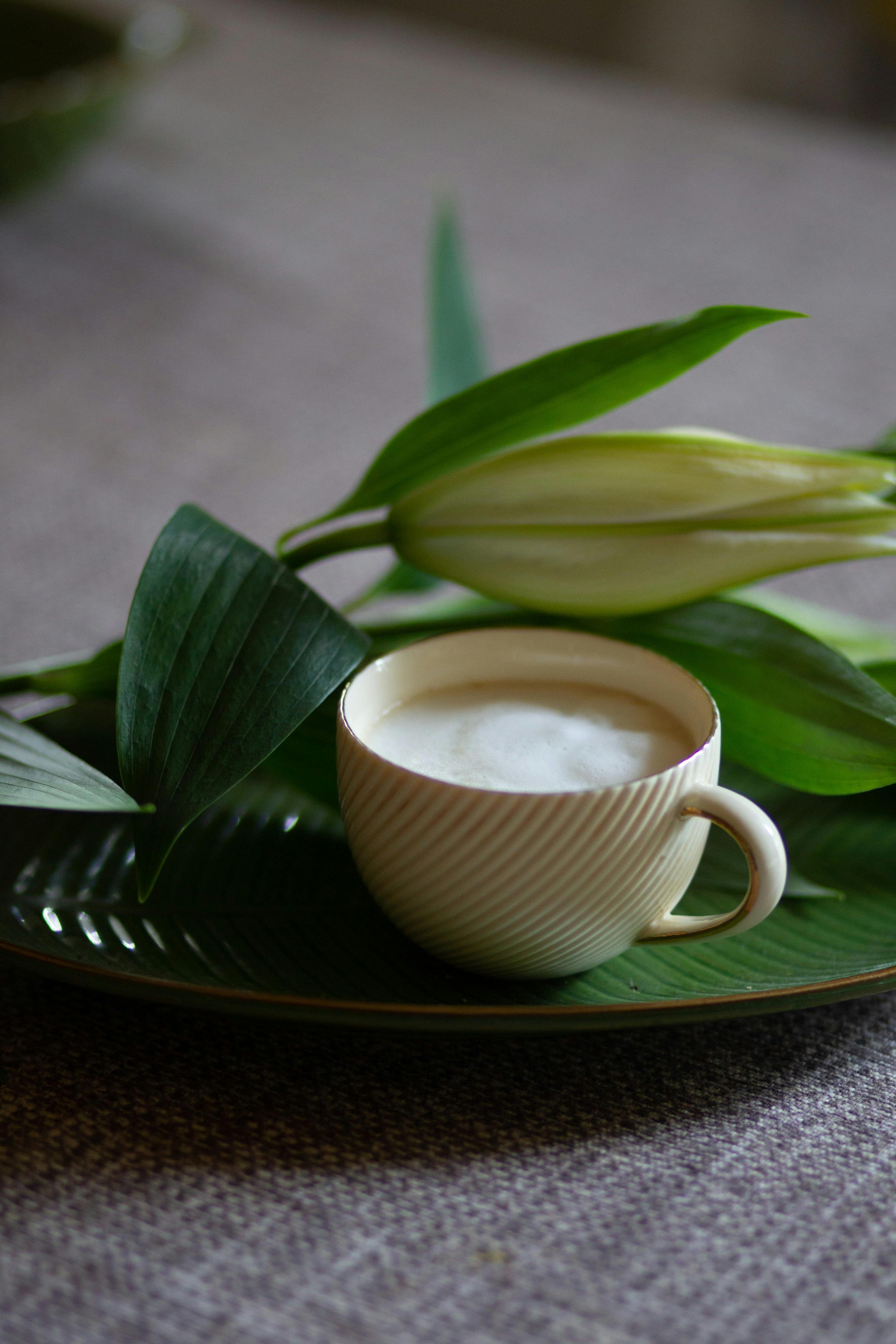 Stylish cappuccino presentation with a fresh lily on a textured surface, offering a serene and aromatic ambiance.
