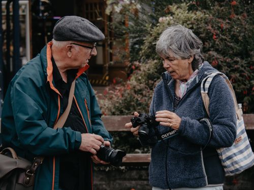 Free Two senior adults examining cameras in an outdoor setting, engaged in a passionate conversation. Stock Photo
