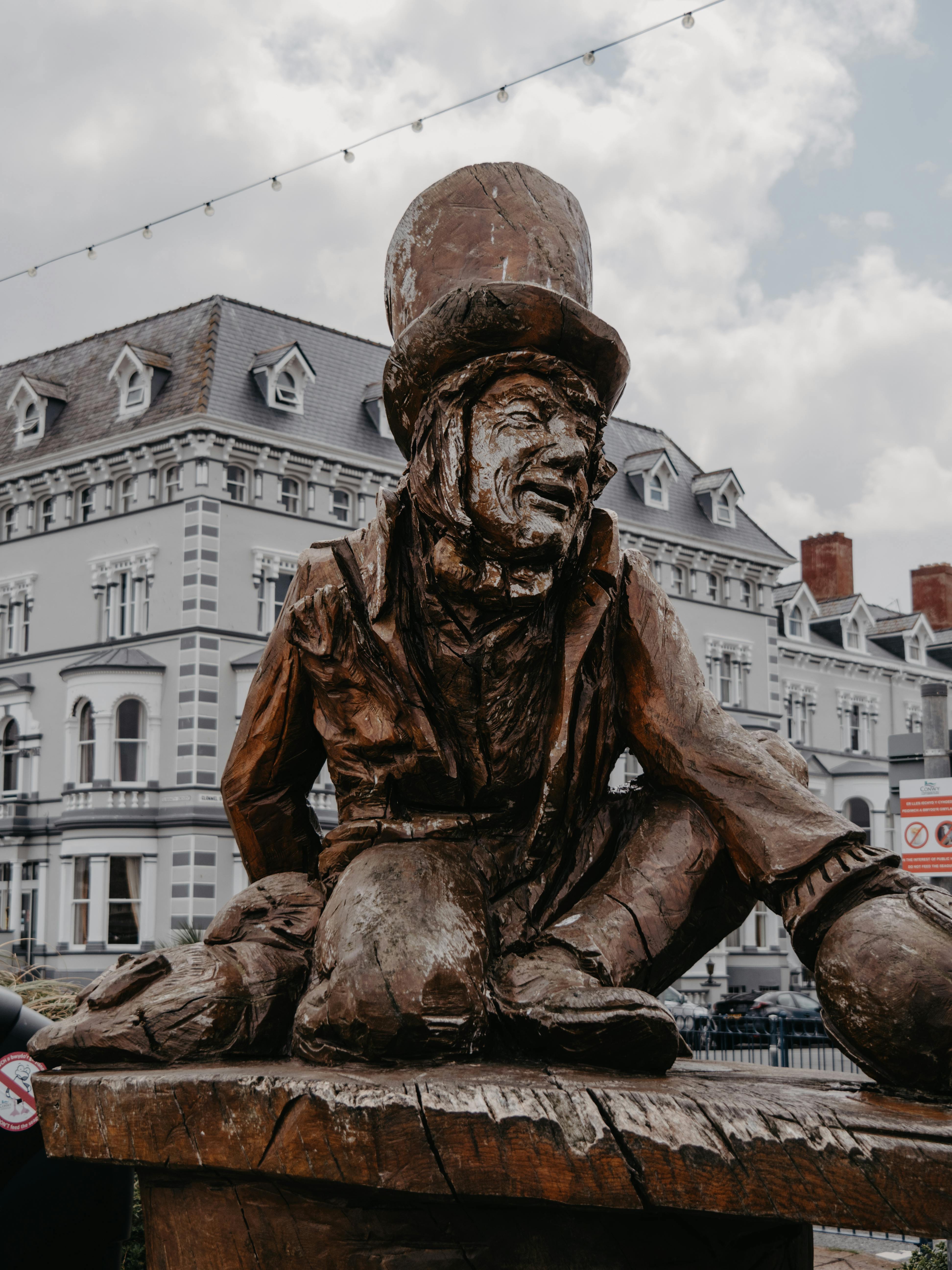 Captivating statue of the Mad Hatter in Llandudno, Wales set against Victorian architecture.