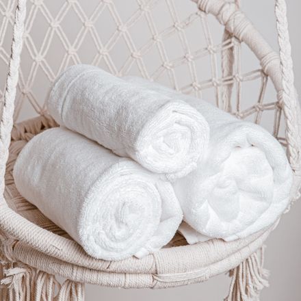Three rolled white towels in a woven basket — Dmitriy Steinke on Pexels