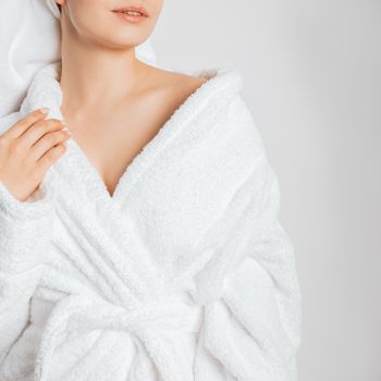 Portrait of a woman in a white fluffy bathrobe, with a towel on her head, posing glamorously.