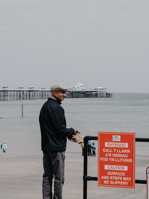 Man Standing near Warning Board in Welsh