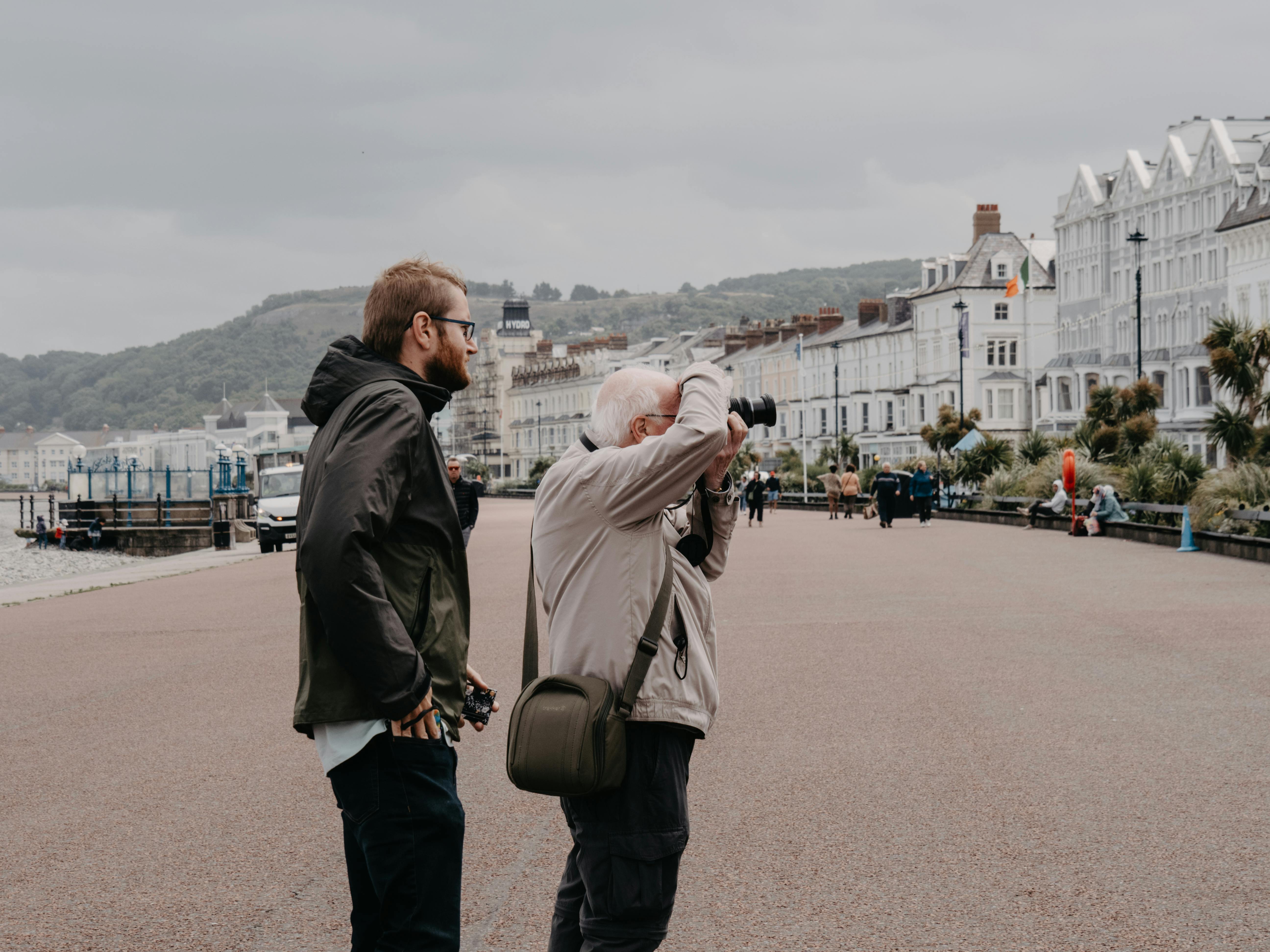 Tourists capturing the charming promenade of Llandudno, Wales on a cloudy day.