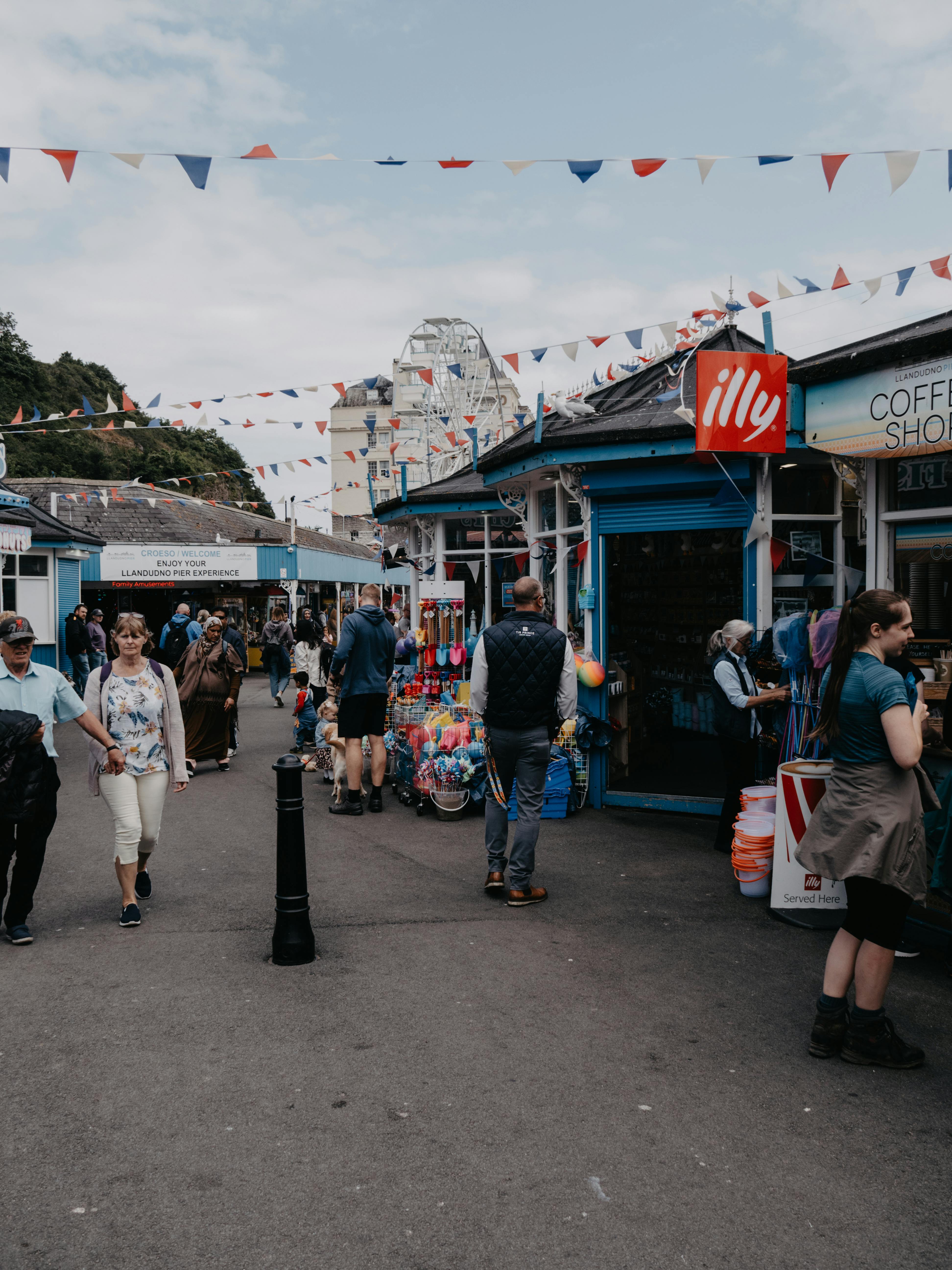 Explore a lively market alley in Llandudno, Wales, filled with people, stores, and vibrant street life.