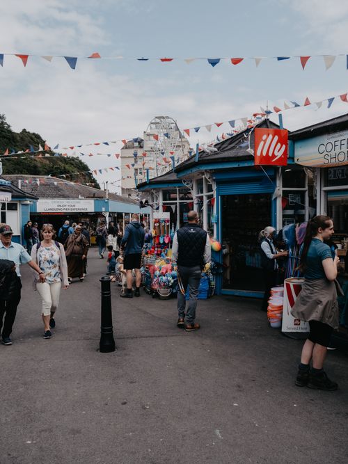 Free Explore a lively market alley in Llandudno, Wales, filled with people, stores, and vibrant street life. Stock Photo