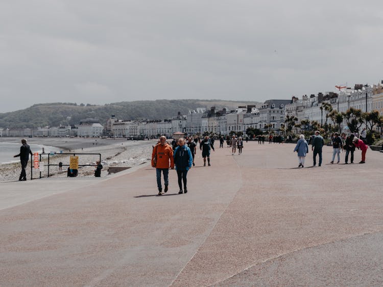 People Walking On Sunlit Promenade In Town