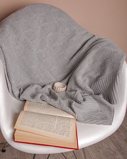 Gratis lagerfoto af åben bog, grå tæppe, hvid lænestol