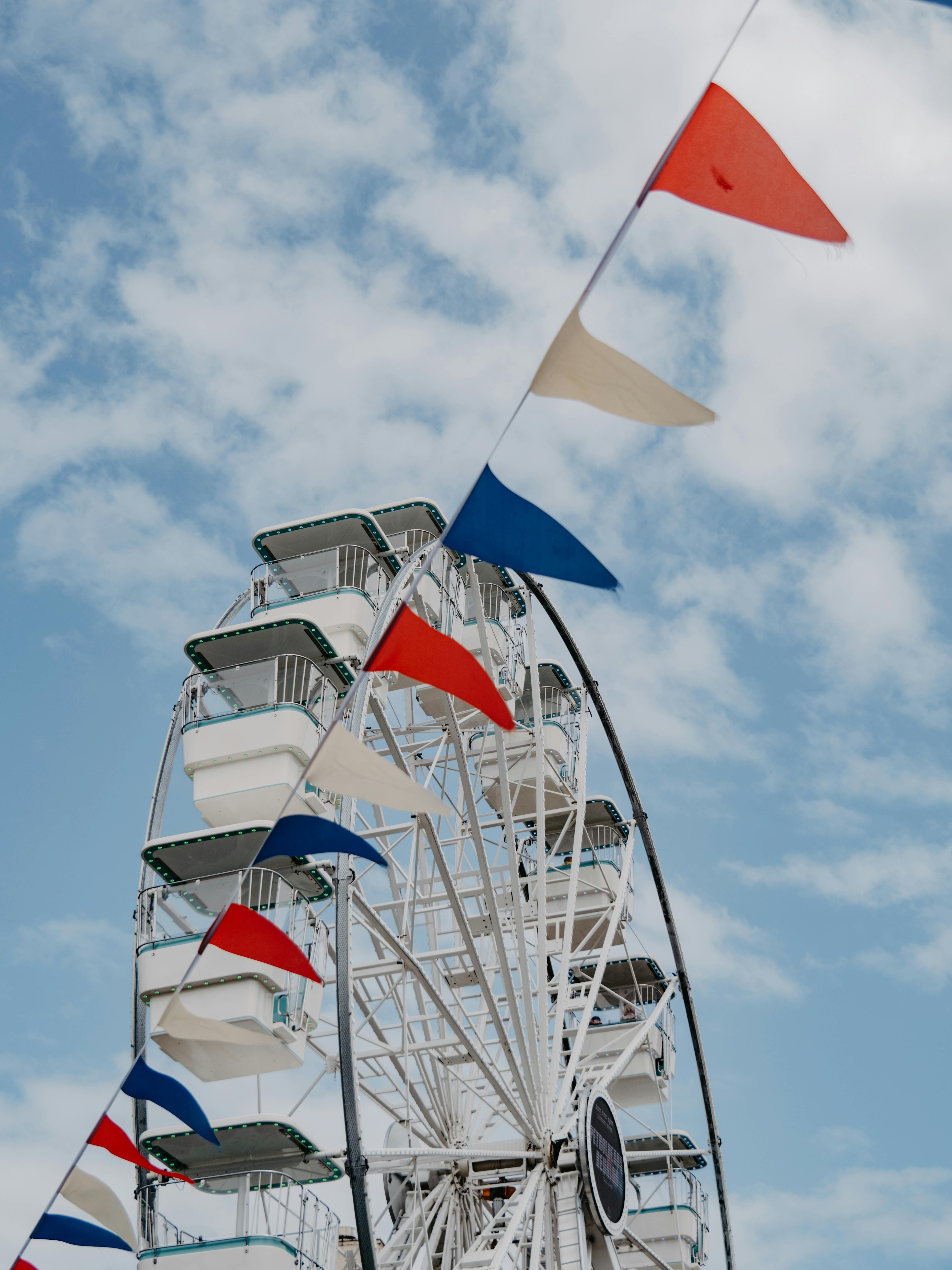 Ferris wheel and vibrant flags against a bright blue sky, capturing a lively amusement park vibe.