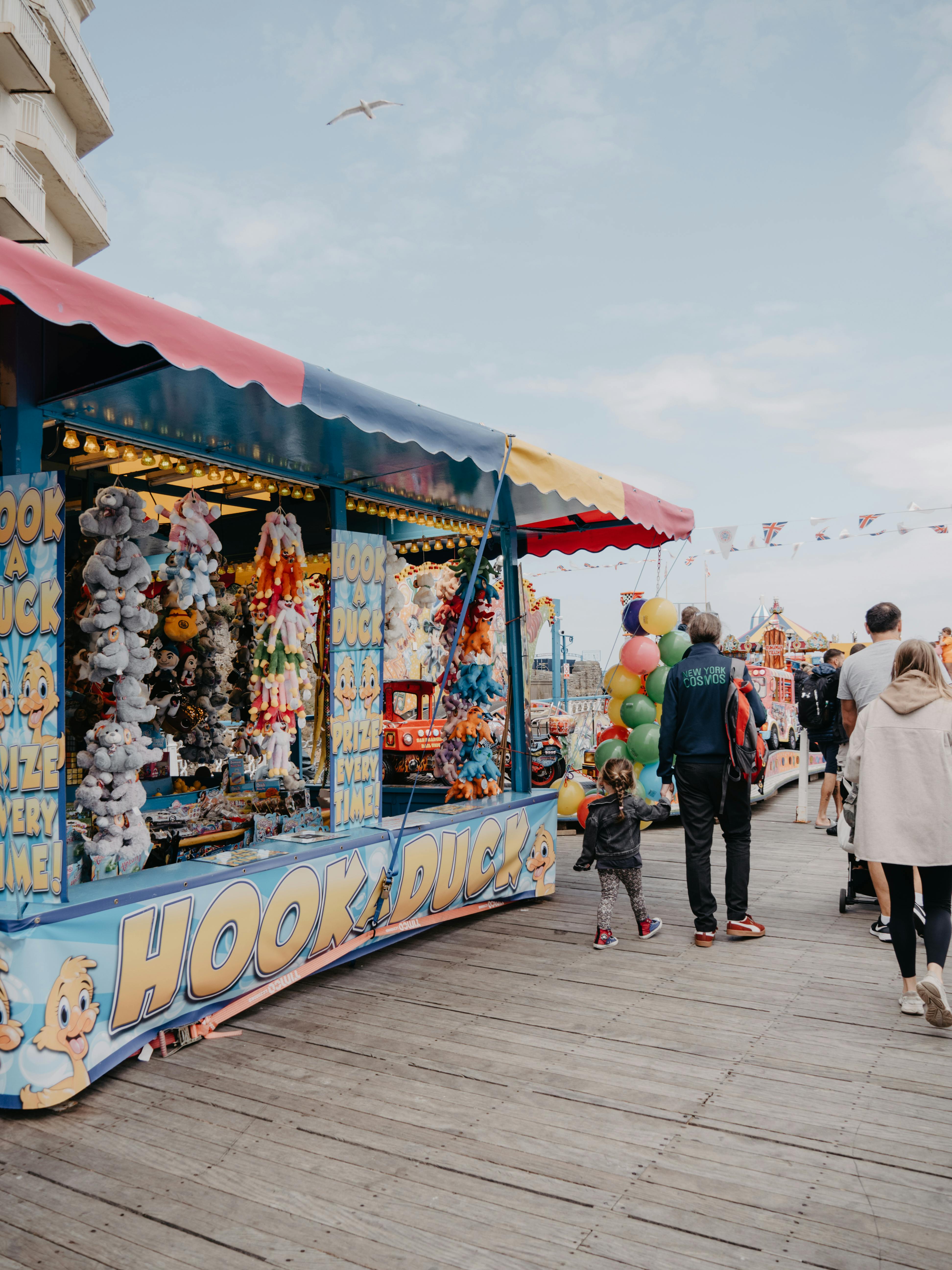 Colorful carnival games and families enjoying a walk on Llandudno Pier in Wales.
