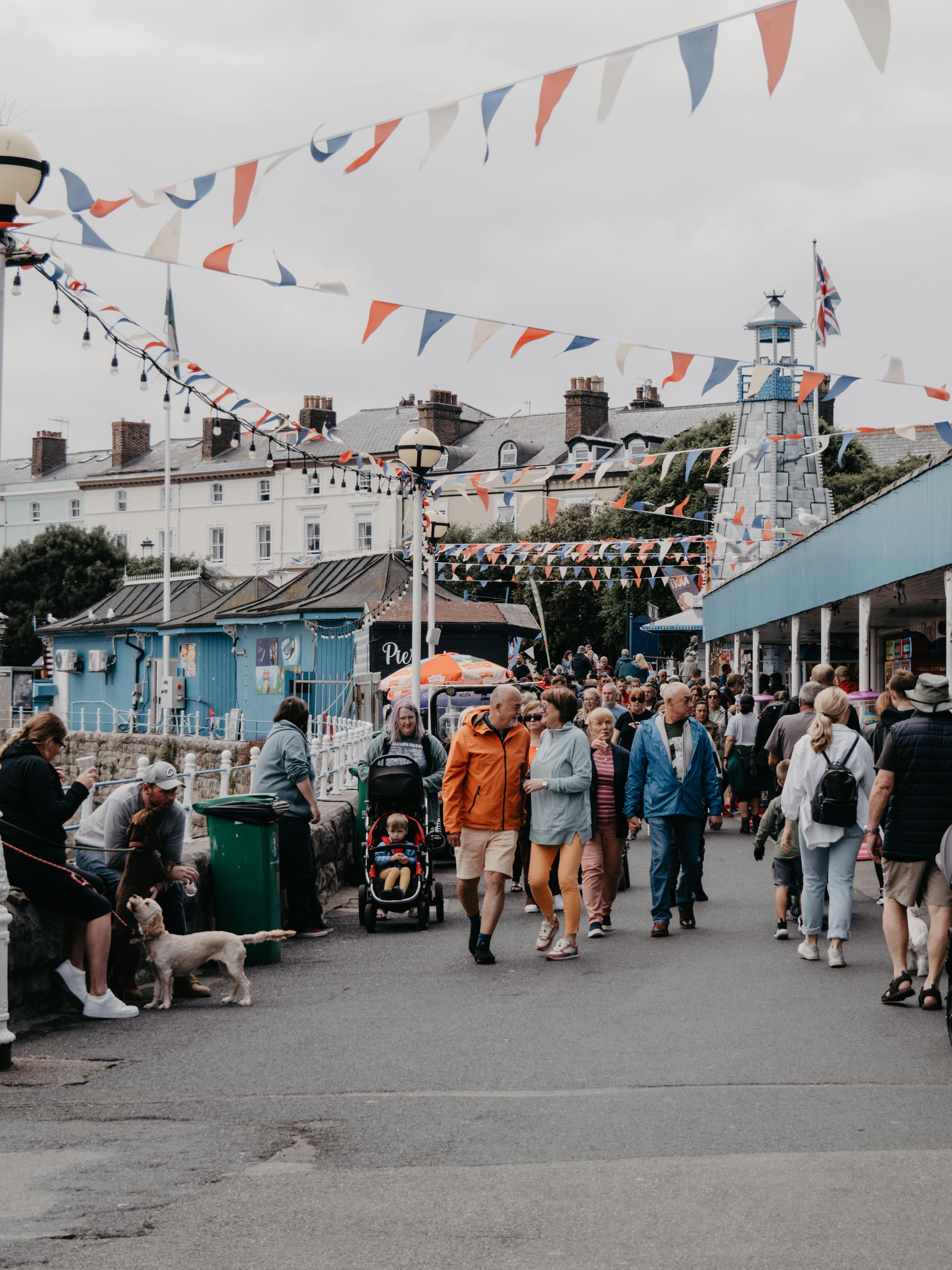 People walking on a lively promenade in Llandudno, Wales, adorned with colorful bunting.