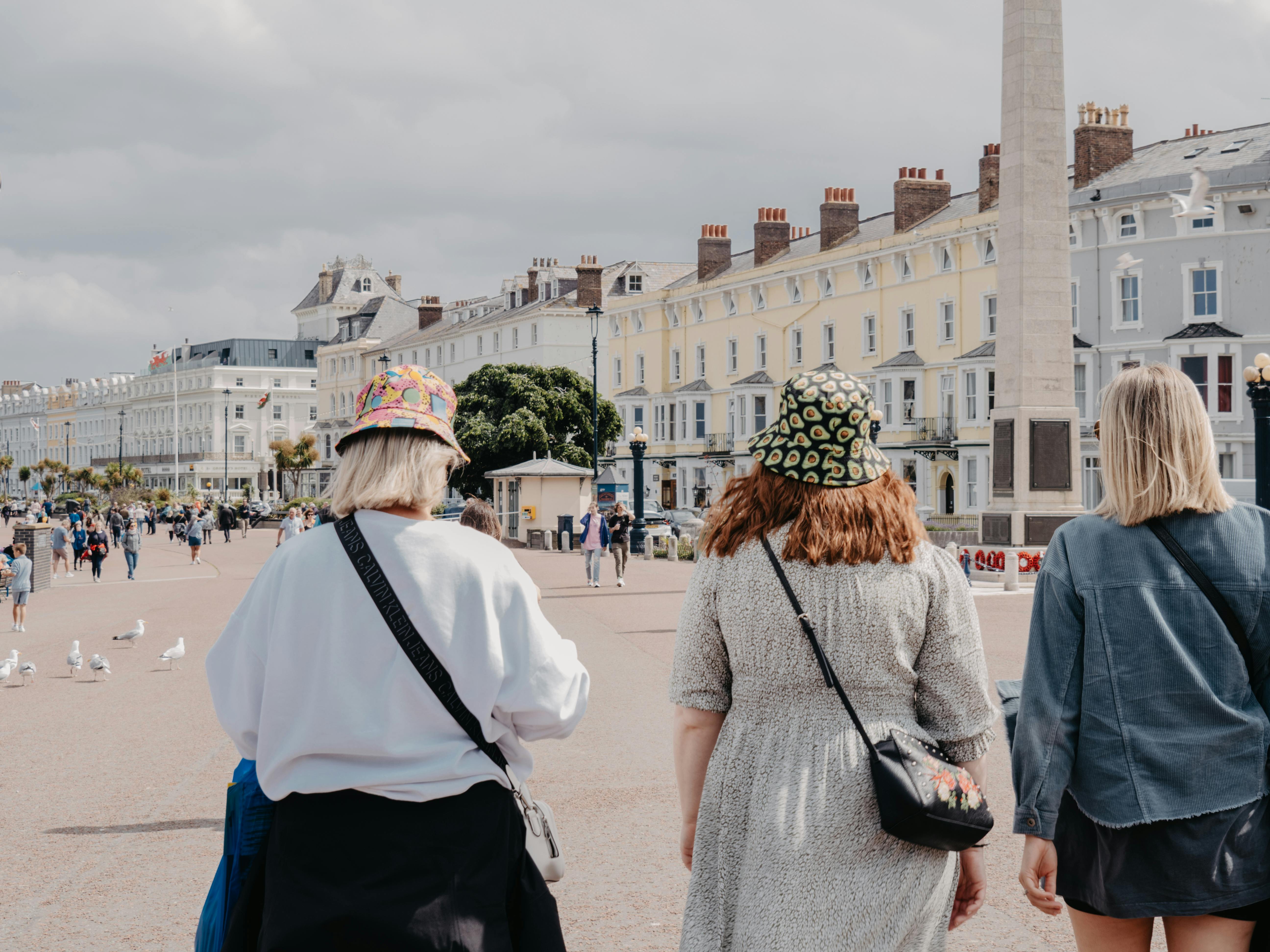 Tourists walking along the scenic promenade in Llandudno, Wales, enjoying a sunny day.