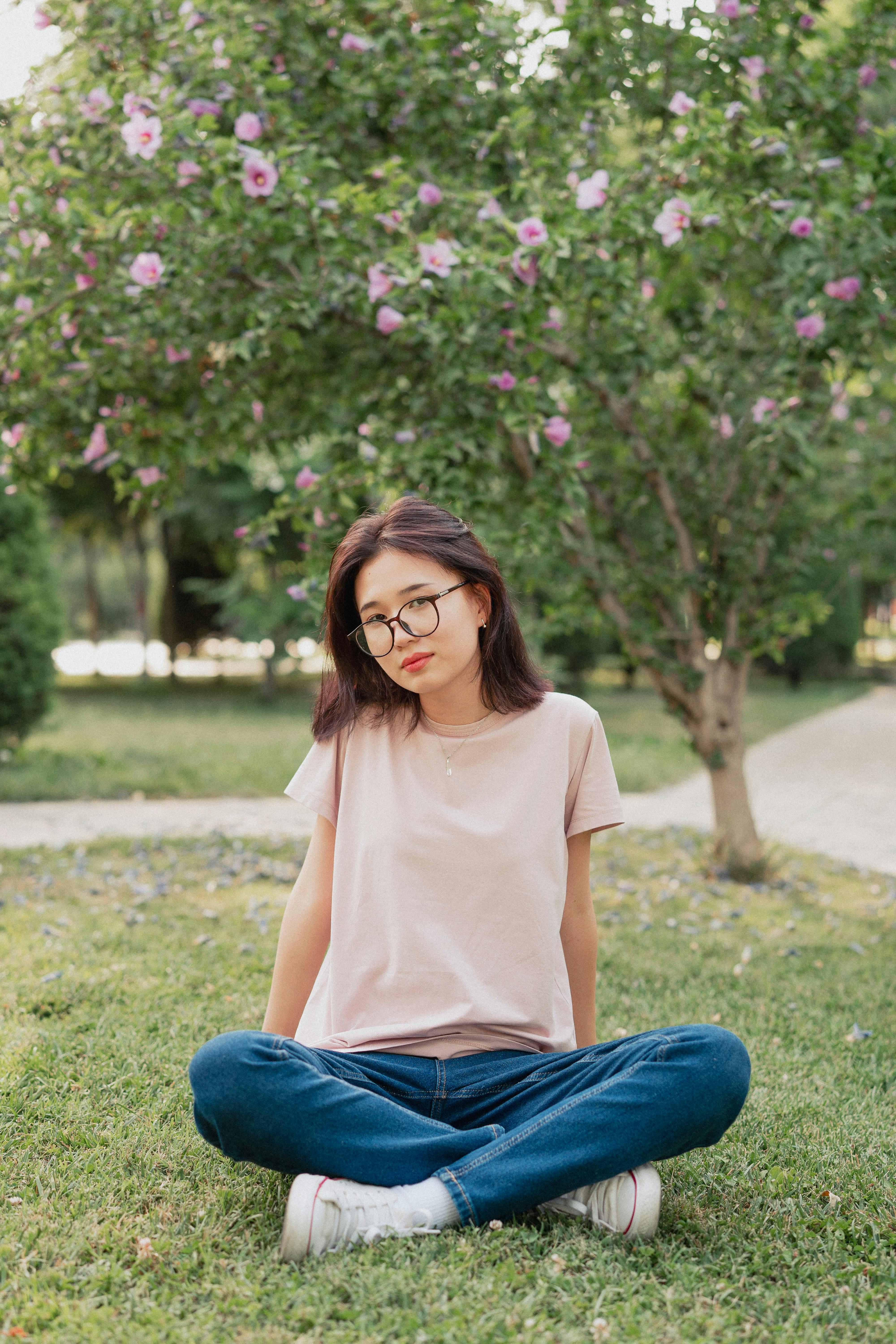 Woman in white long sleeve shirt and blue denim jeans sitting on green grass  field during photo – Free Clothing Image on Unsplash