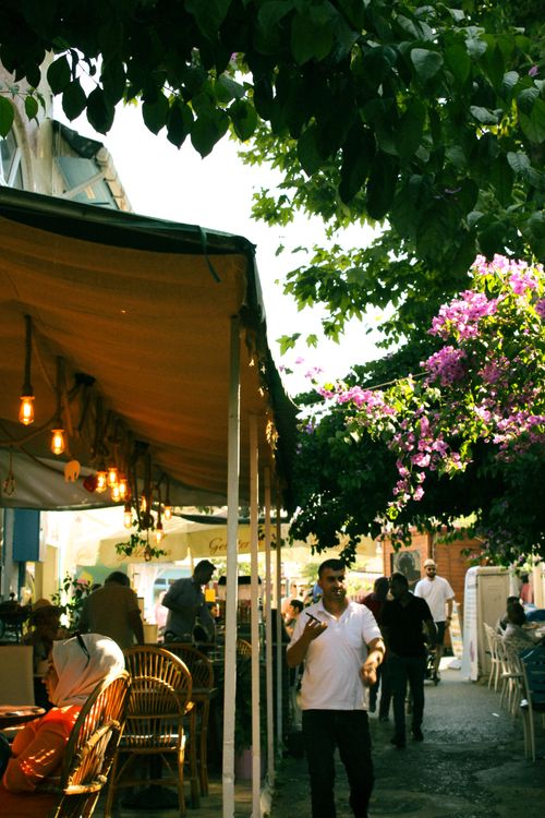 Free People enjoying a sunny day at a bustling outdoor cafe, surrounded by blossoms and urban scenery. Stock Photo