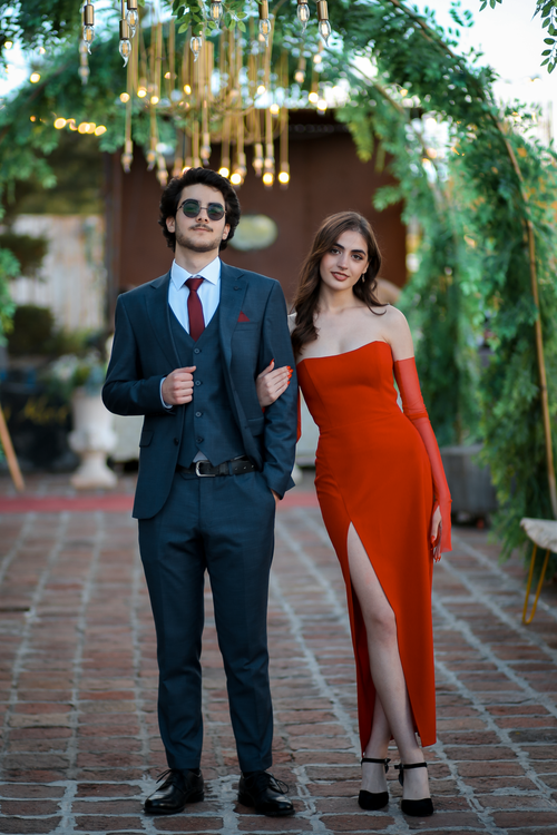 Free Stylish couple posing at a luxurious garden party. Outdoor setting with festive lights. Stock Photo