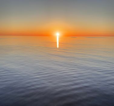 A breathtaking view of the sunset casting vivid colors over a tranquil sea.