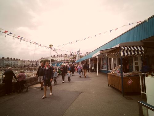 Free Lively outdoor market in Llandudno, Wales with people, shops, and festive flags. Stock Photo