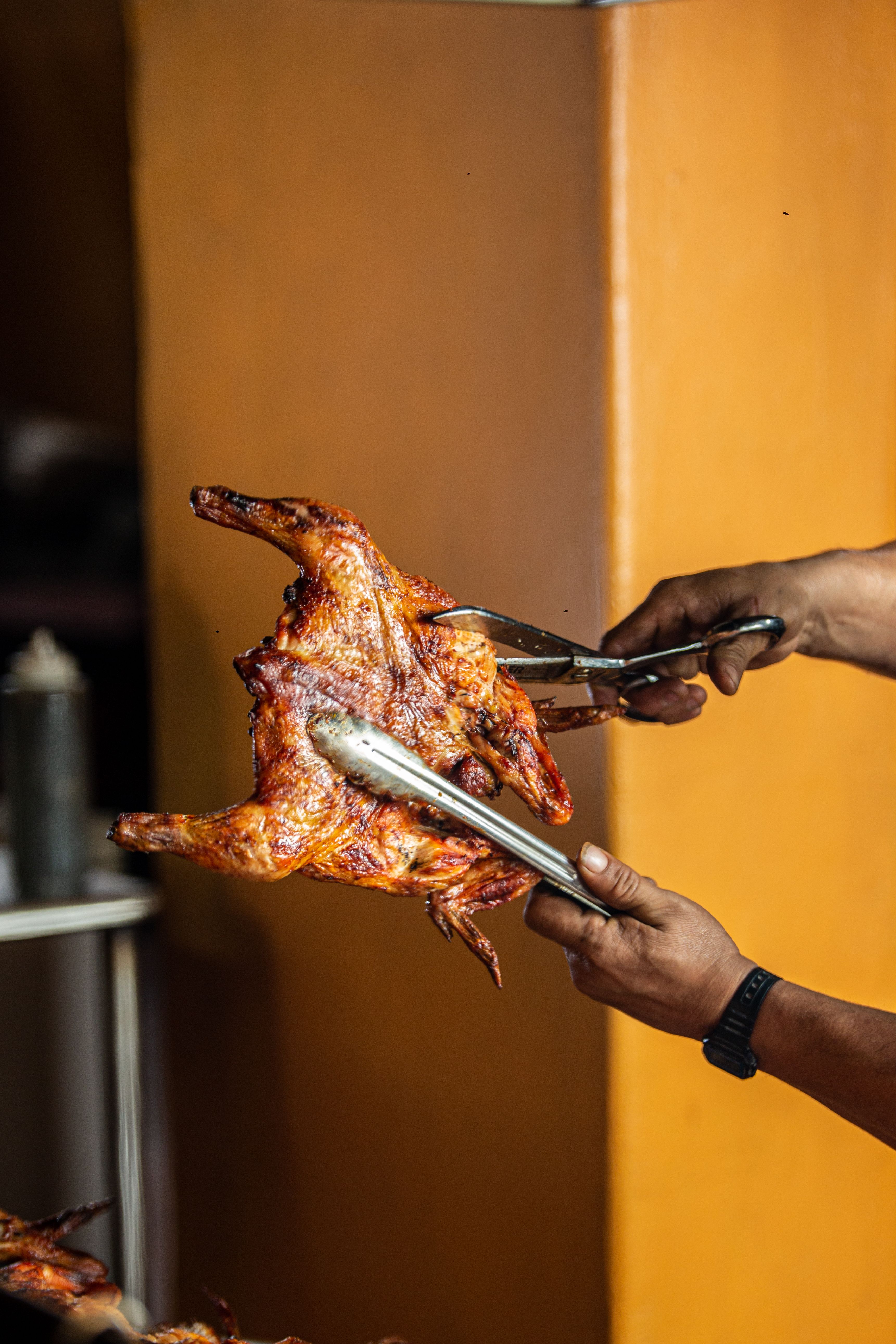 Close-up of a grilled chicken being served, showcasing delicious crispy skin and cooked perfection.