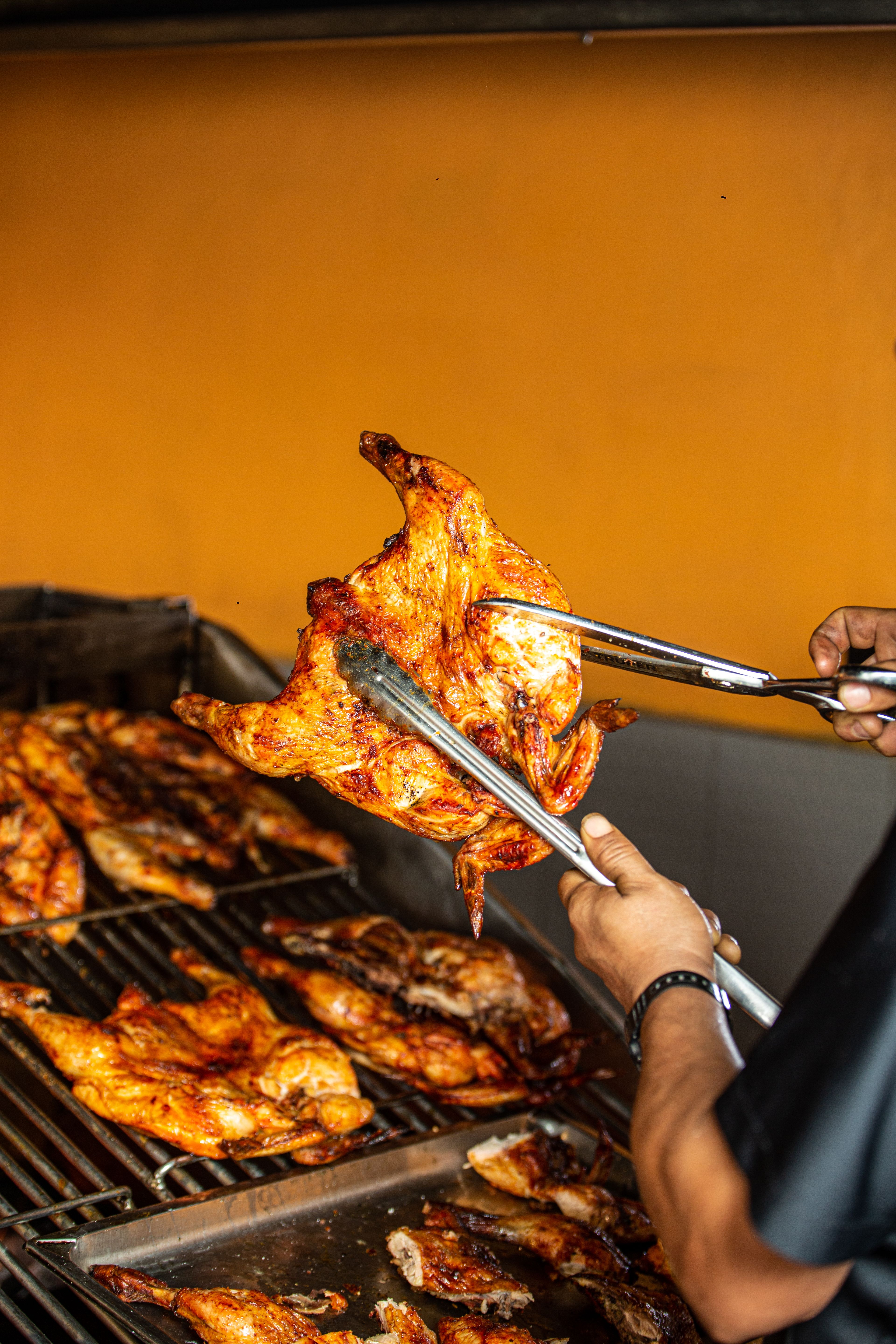 Juicy grilled chicken on BBQ grill with tongs, perfect for summer cookouts.
