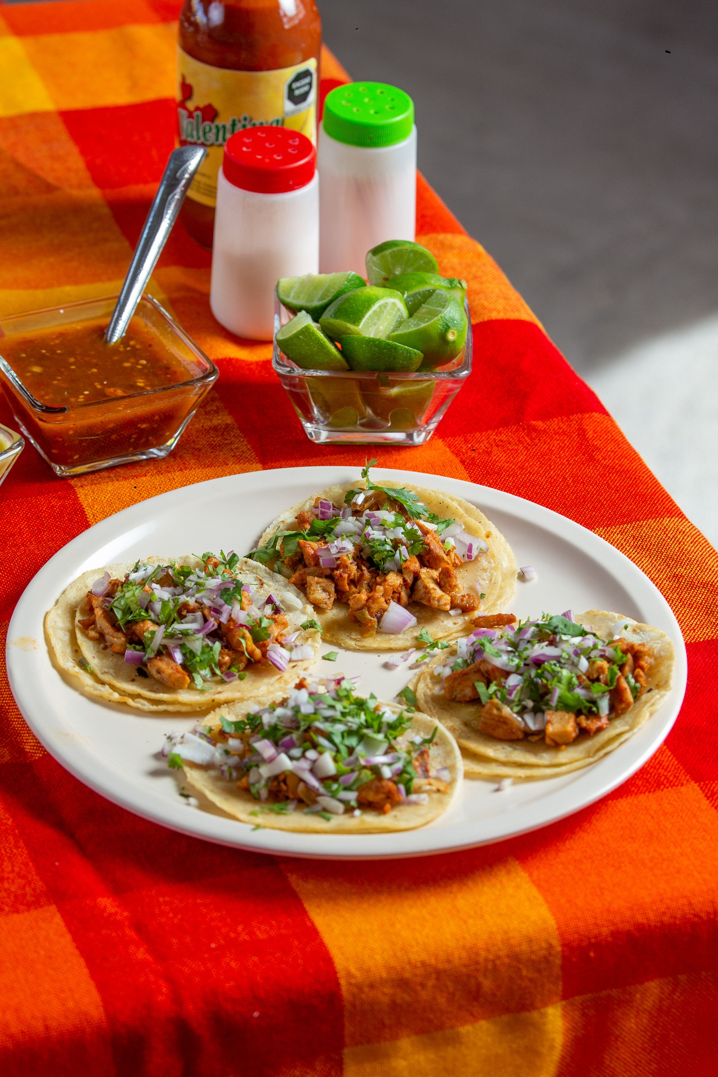 Small street tacos with lime and salsa on a platter