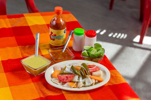 Free Colorful Mexican ceviche served with hot sauce, lime, and salsas on a vibrant tablecloth. Stock Photo