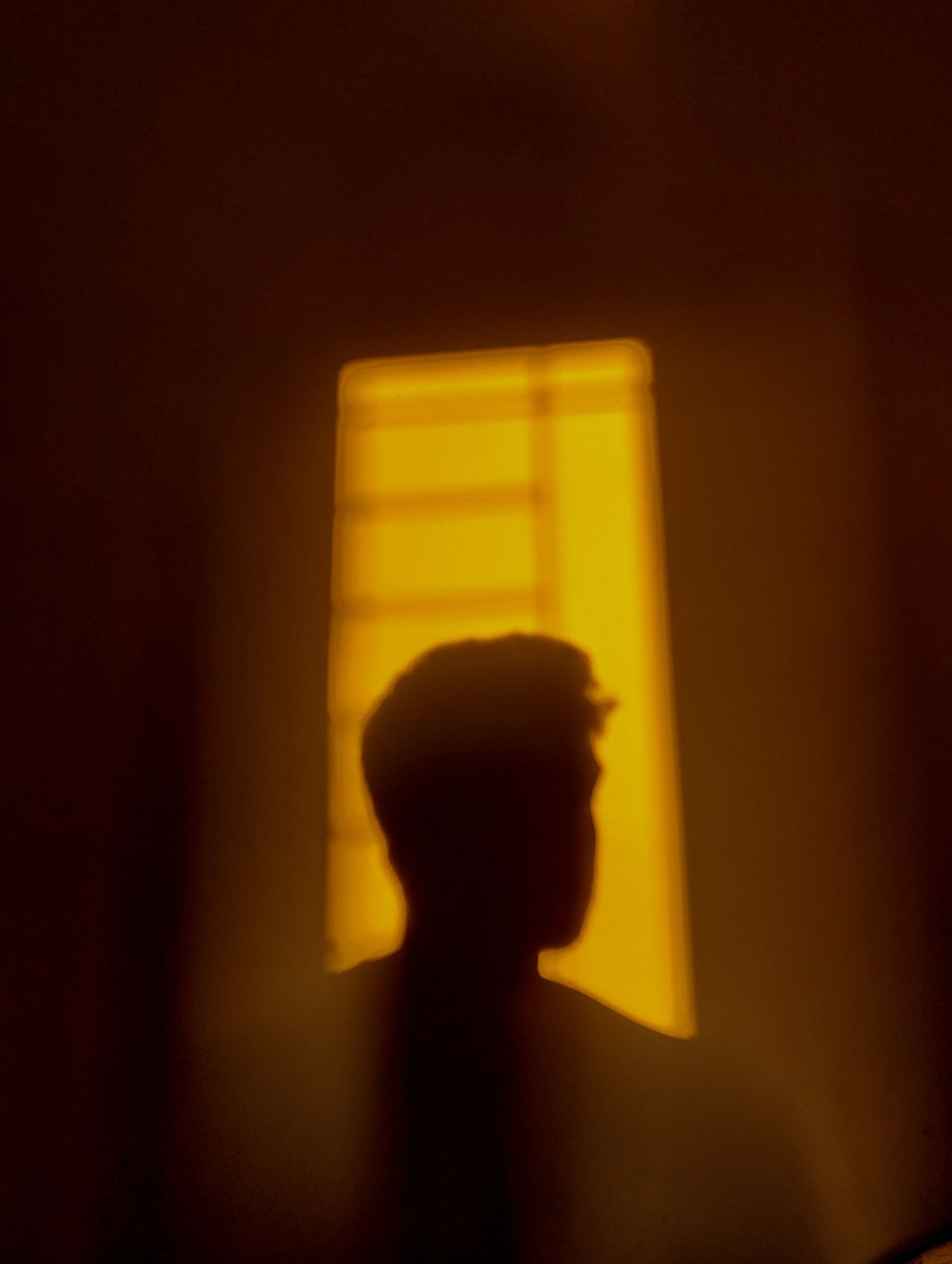 Silhouette of a man against a glowing window, representing the unseen patterns behind financial self-sabotage