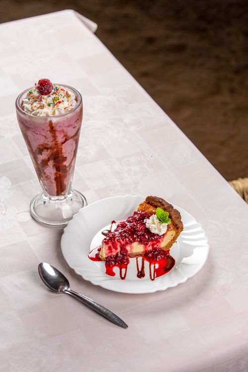 Free Delicious raspberry cheesecake slice with cream and milkshake, perfect for a sweet treat. Stock Photo