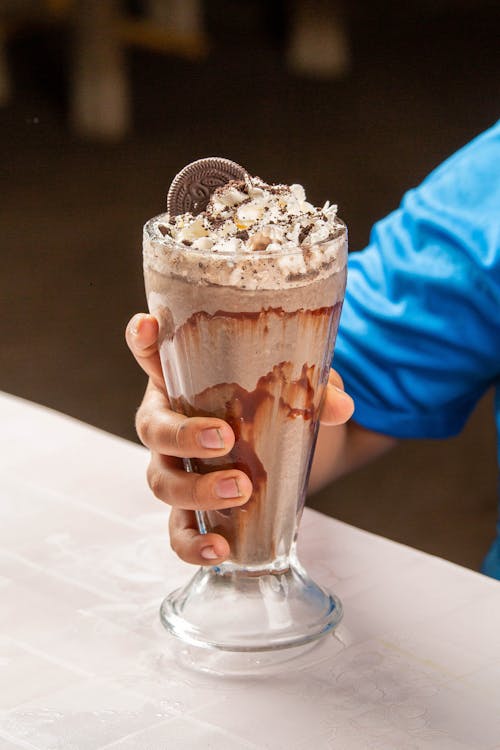 Hand of a Person Holding a Dessert in a Big Glass