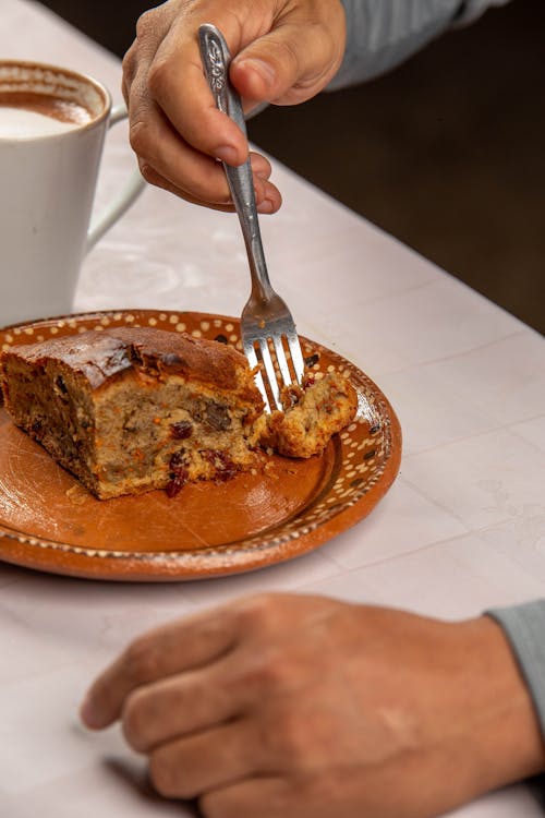 Hand Eating Yeast Cake with Fork
