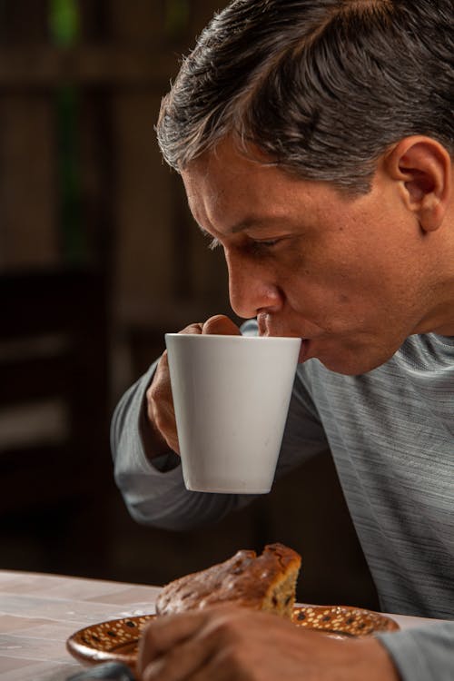 Man Drinking from a Cup over a Slice of Pie