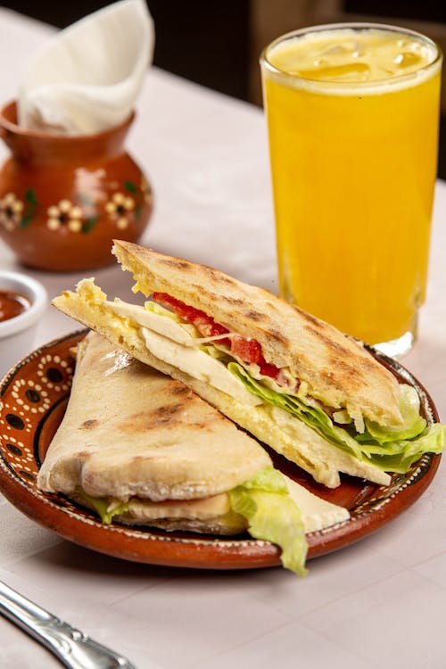 Pita Sandwich Set on Plate next to Glass of Orange Juice