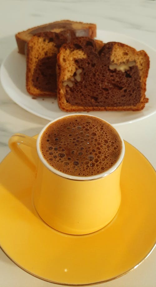 Yellow Cup of Coffee next to Slices of Pound Cake Served on Plate