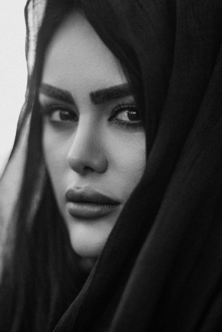Striking black and white portrait of a woman in a hijab showcasing deep emotion and strength.