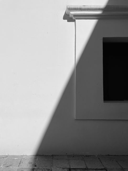 Black and white minimalist photo of a building facade with sharp shadows in Oaxaca, Mexico.